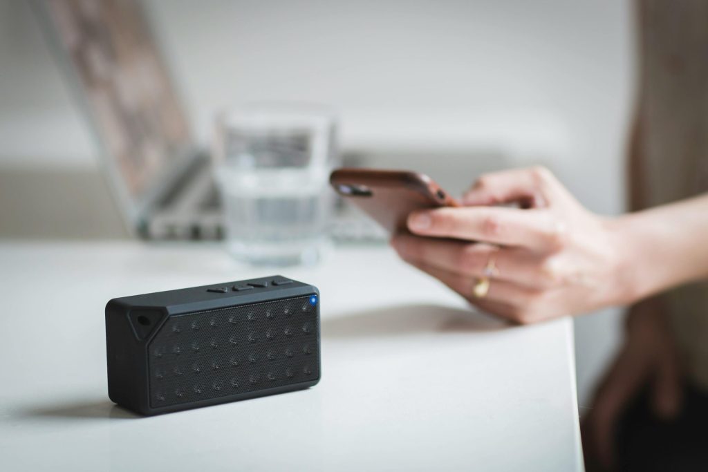 Person connecting a smartphone to a wireless speaker indoors, foreground focus.