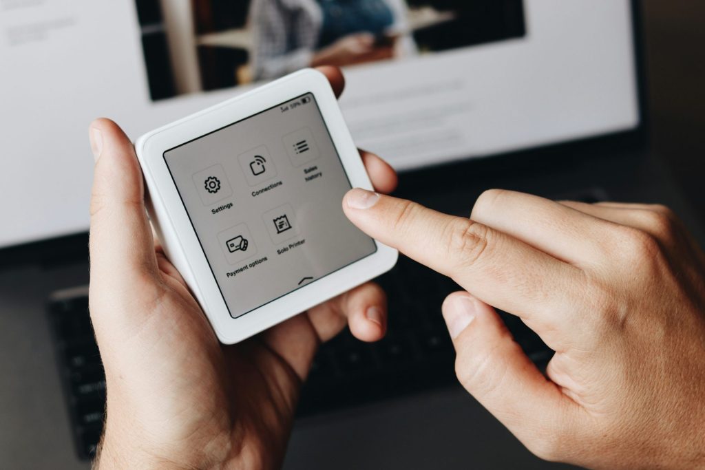 A person holding a tablet in front of a laptop
